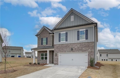 Craftsman inspired home with board and batten siding, brick siding, an attached garage, and driveway