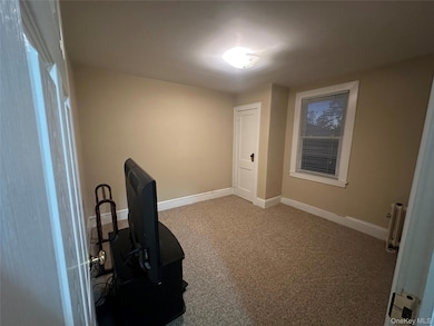 Office area featuring light colored carpet and radiator