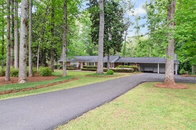 Ranch-style home featuring driveway, a carport, and a front yard