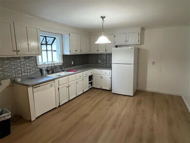 Kitchen featuring white appliances, white cabinets, backsplash, light wood-type flooring, and pendant lighting