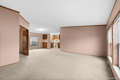 Unfurnished living room with ornamental molding and light carpet