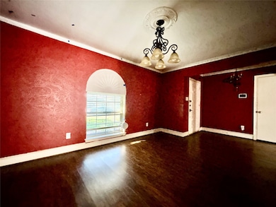 Unfurnished room featuring a chandelier, dark wood finished floors, and a textured wall