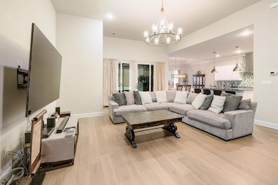 Living area with light wood-style flooring, recessed lighting, a chandelier, and french doors