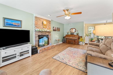 Living area featuring ceiling fan, a brick fireplace, wood finished floors, and recessed lighting