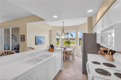 Kitchen with white appliances, sink, light tile pa