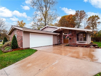 View of front of property with driveway, brick siding, and a garage