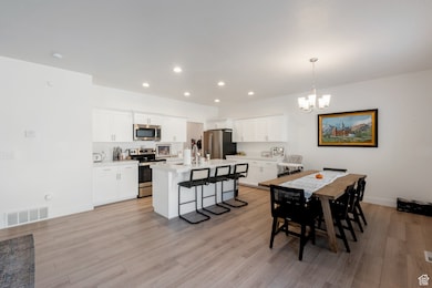 Dining area with light wood-type flooring, recessed lighting, and a chandelier