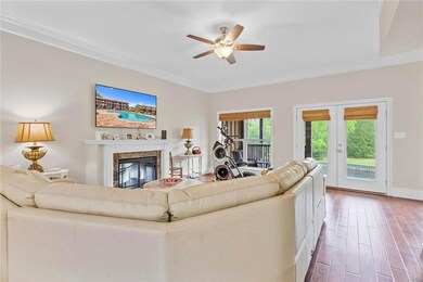 Living area with ceiling fan, wood finished floors, a premium fireplace, and crown molding