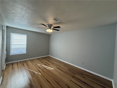 Empty room featuring hardwood / wood-style flooring, a textured ceiling, and ceiling fan