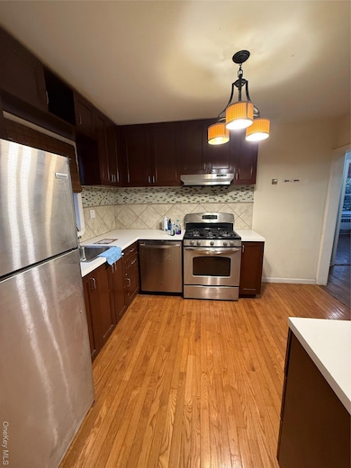Kitchen with refrigerator, decorative backsplash, dark brown cabinetry, and stainless steel range oven