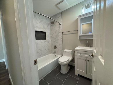 Full bath featuring shower / tub combination, vanity, and dark tile patterned flooring