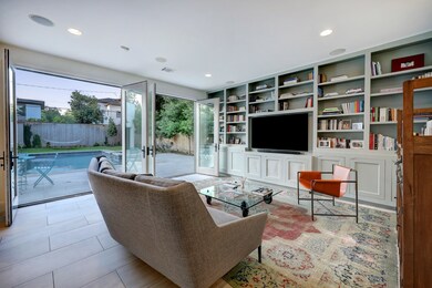 A wall of custom cabinetry, built-in LG television and French doors that open to the outdoor oasis make the family room a favorite gathering spot. Two sets of French doors open the space entirely to the rear yard creating a seamless connection to the outdoor space.