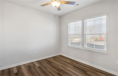 Spare room with baseboards, dark wood-style floors, and a ceiling fan