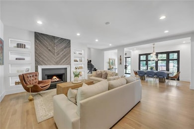 Living room featuring a fireplace, light wood-style flooring, custom bookshelves, and recessed lighting