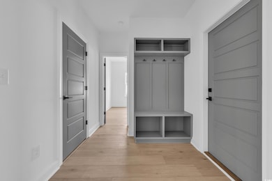 Mudroom featuring light wood-style flooring and baseboards