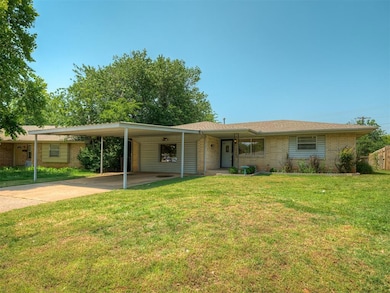 Single story home featuring brick siding, driveway, a front yard, and a carport