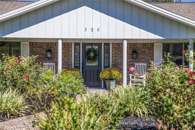 View of front of house featuring a shingled roof, a porch, brick siding, and board and batten siding