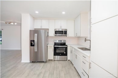 Kitchen featuring stainless steel appliances, light countertops, light wood finished floors, white cabinets, and recessed lighting