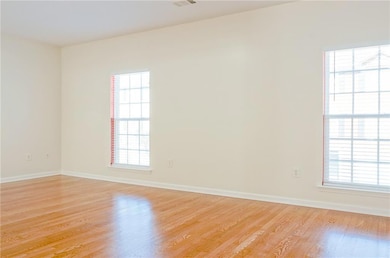 Unfurnished room with a wealth of natural light, light wood finished floors, and baseboards