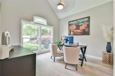 Office space with high vaulted ceiling, light wood finished floors, a ceiling fan, and baseboards