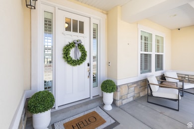 Entrance to property featuring covered porch, stone siding, and stucco siding