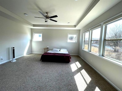 Carpeted bedroom with a raised ceiling, baseboards