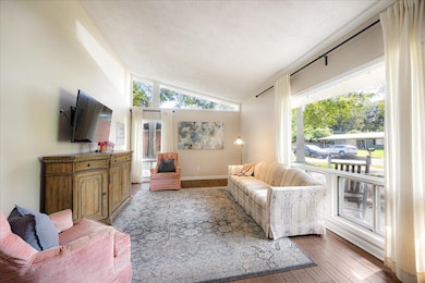 Living room with vaulted ceiling, light wood-style flooring, and baseboards