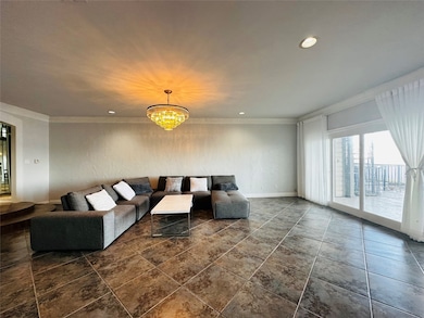 Living room with a notable chandelier, ornamental molding, and dark tile floors