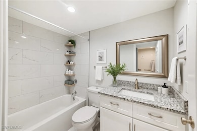 Bathroom with toilet, vanity, and  shower combinat