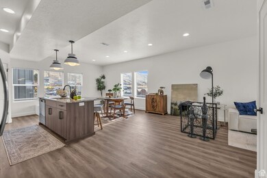 Kitchen featuring wood finished floors, a sink, baseboards, a center island with sink, and a breakfast bar area