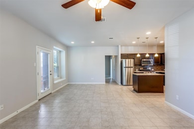 Kitchen with tasteful backsplash, pendant lighting, appliances with stainless steel finishes, light tile patterned flooring, and a center island