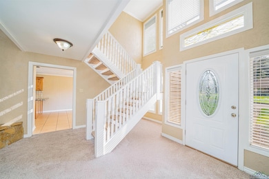 Carpeted foyer featuring stairs, baseboards, and tile patterned flooring