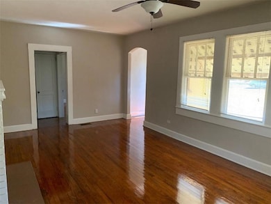 Unfurnished room featuring arched walkways, ceiling fan, wood finished floors, and baseboards