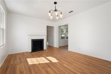Unfurnished living room with a chandelier, a fireplace, and wood finished floors
