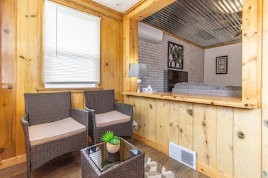 Living area featuring brick wall, hardwood / wood-