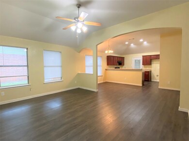 Unfurnished living room featuring dark hardwood / wood-style floors, ceiling fan with notable chandelier, and lofted ceiling