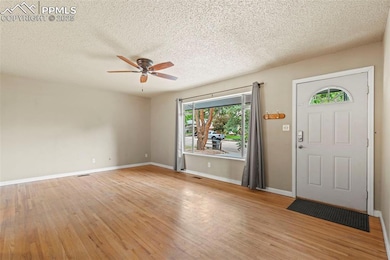 Foyer with a ceiling fan, light wood finished floors, and a textured ceiling