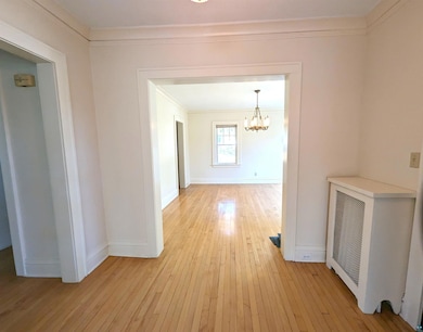 Corridor with crown molding, a notable chandelier,