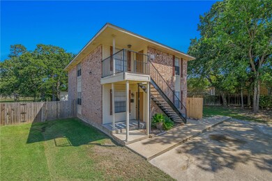 View of front of property with brick siding, a patio, a fenced backyard, stairway, and a balcony
