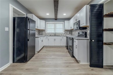 Kitchen featuring black appliances, white cabinets