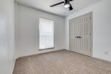 Unfurnished bedroom featuring a closet, multiple windows, light colored carpet, and ceiling fan