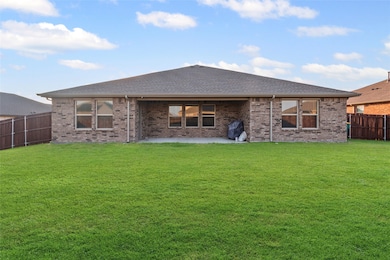 Rear view of property featuring a fenced backyard, brick siding, a patio area, and roof with shingles