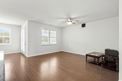 Unfurnished living room with dark wood-style floors, plenty of natural light, and a ceiling fan