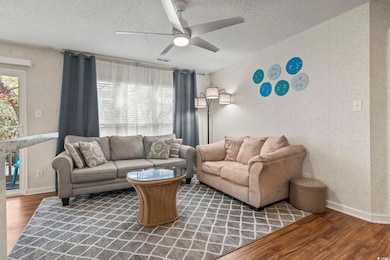 Living room featuring ceiling fan, dark hardwood /