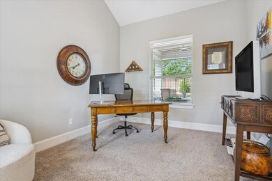 Carpeted office featuring vaulted ceiling and bas