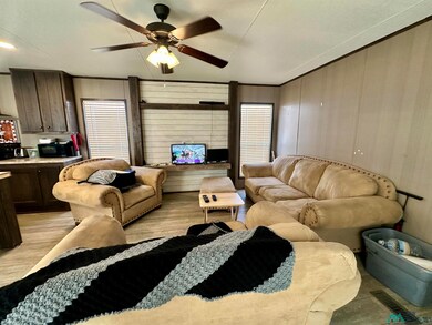 Living room with light wood finished floors, a ceiling fan, and wood walls