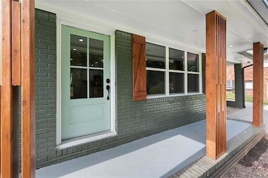 Entrance to property featuring covered porch and brick siding