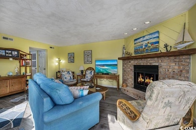 Living room with a textured ceiling, a brick firep