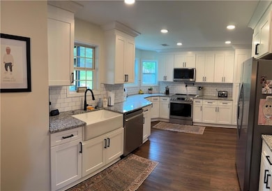 Kitchen with stainless steel appliances, a farm sink, white cabinetry, tasteful backsplash, and recessed lighting