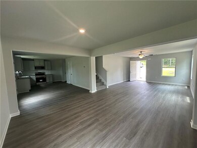 Unfurnished living room with stairway, dark wood-type flooring, and a ceiling fan